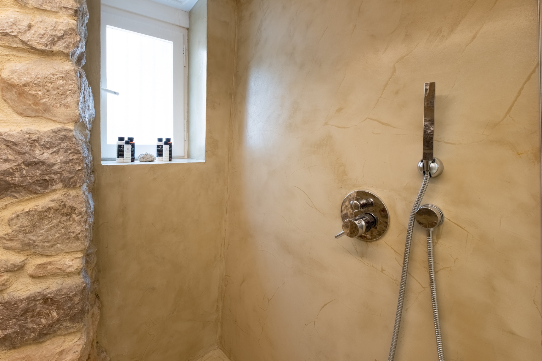 Walk-in shower with microcement walls and natural stone detailing.