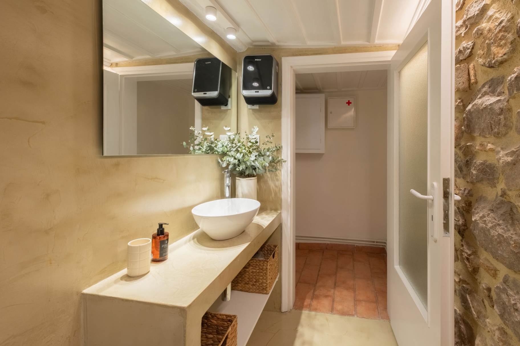 Washroom with stone vanity, vessel basin, and eucalyptus accents.