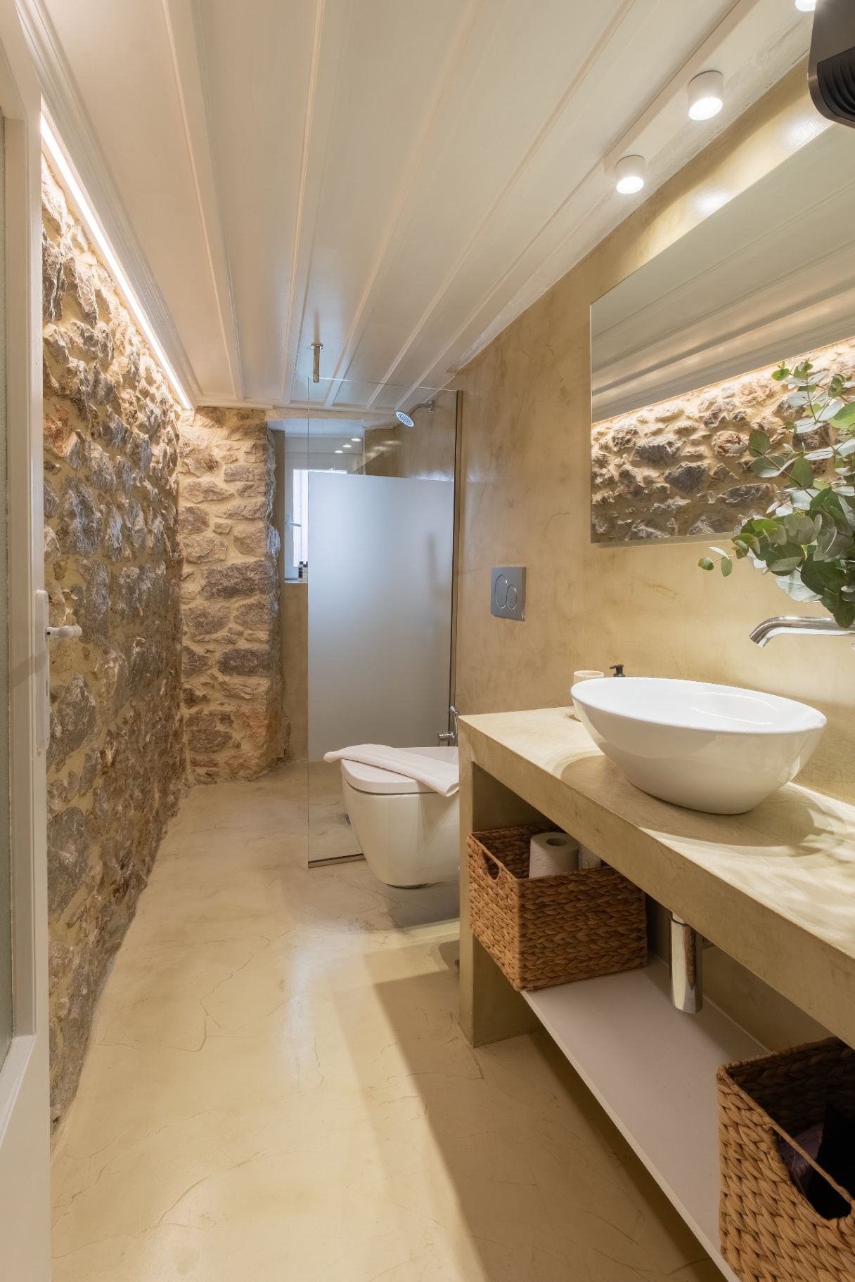 Bathroom with exposed stone wall, walk-in shower, and stone vanity.